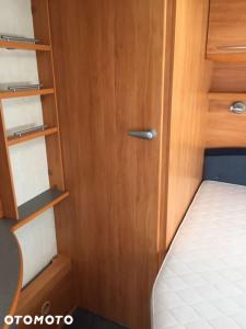 mały pokój z drewnianymi drzwiami i łóżkiem w obiekcie Przyczepa kemping Chałupy 3 Półwysep Hel w Chałupach