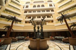 a lobby of a hotel with palm trees and a statue at Welcomhotel by ITC Hotels, Devee Grand Bay, Visakhapatnam in Visakhapatnam