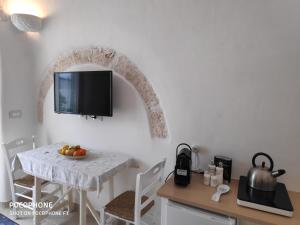 a kitchen with a table and a tv on the wall at Dimora Sumerano in Alberobello