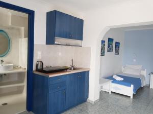 佩里萨Roula Villa Studios & Apartments的厨房配有蓝色橱柜、水槽和床。