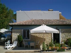 a small house with a table and an umbrella at Sofia Apartments in Paralía Iríon