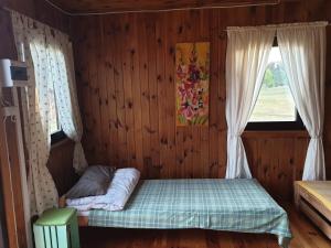 a bedroom with a bed in a wooden room with a window at Domek Wieloosobowy - Agroturystyka in Przetycz