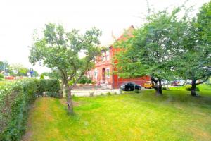a yard with two trees in front of a red house at Private Rooms in Hannover