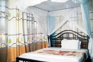 1 dormitorio con cama con dosel y cortinas en Jaden Hotel & Lounge - Arusha, en Arusha