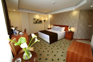 a hotel room with a bed and a table at Tuzla Garden Hotel & Spa in Tuzla