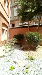 a garden with rocks and trees in front of a building at Résidence le Pastel François Verdier in Toulouse