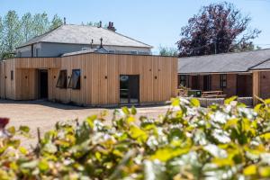 a barn with a building in the background at Oak – Three Tuns Apartments in Pettistree