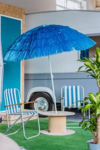 a table with a blue umbrella and two chairs at Towed Town Camping and Event Space in Bristol