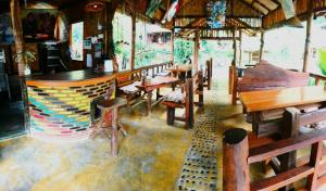 a restaurant with wooden tables and chairs in a room at Eriono guest house Bukit lawang in Bukit Lawang