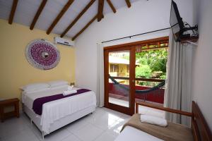 a bedroom with a bed and a window with a hammock at Pousada Quintessência in Arraial d'Ajuda