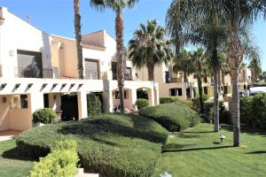a large house with palm trees and bushes at Townhouse overlooking the pool in San Javier
