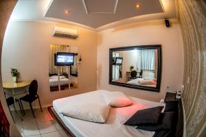 a bedroom with a bed and a mirror and a table at Motel Paradiso - Passo Fundo in Passo Fundo
