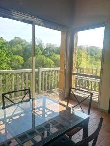 Cette chambre dispose d'un balcon avec une table et des chaises en verre. dans l'établissement Gîtes hunières, à Fourneville