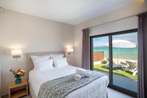 a bedroom with a bed and a view of the ocean at Tiamo Secrets Beach Front by TravelPro - Vourvourou Halkidiki in Vourvourou