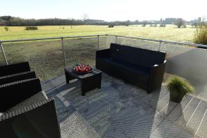 a balcony with a couch and a table and a field at Le 42 in Durbuy