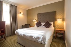 um quarto de hotel com uma cama grande e uma cadeira em Apollo Hotel em Basingstoke