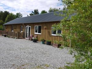 a small wooden cabin with a gravel yard at Roe Deer Cottage in Beauly
