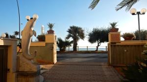 una statua di un cane su un cancello con la spiaggia sullo sfondo di Hotel Delfino a Laigueglia