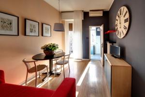 a living room with a table and a clock on the wall at Residence Pian della Nave in Milan