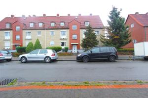zwei Autos auf einem Parkplatz vor den Häusern geparkt in der Unterkunft Private Apartment in Hannover