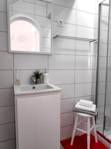 a white bathroom with a sink and a stool at House Seven in Horta