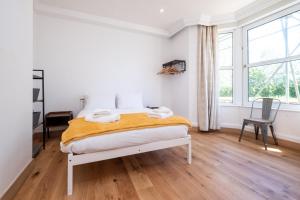 a white bedroom with a bed and a window at Birch – Three Tuns Apartments in Pettistree