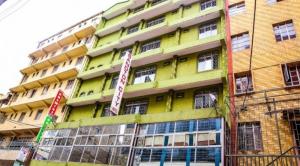 ein gelbes Gebäude mit Schildern davor in der Unterkunft Sandton City Hotel in Nairobi