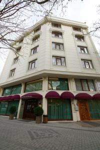 un edificio alto de color blanco con puertas y ventanas verdes en Tuzla Garden Hotel & Spa en Tuzla