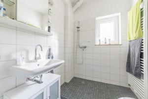 ein weißes Bad mit einem Waschbecken und einem Fenster in der Unterkunft Private Apartment in Hannover