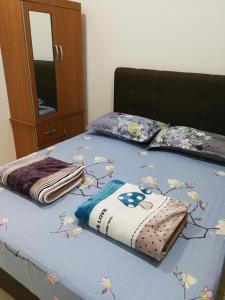 a bed with a blue blanket with flowers on it at Address No 915, Lorong Uni Central 13, Taman Uni Central, Kuching Samarahan Expressway in Kuching