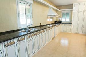 uma grande cozinha com armários brancos e um lavatório em Villa Grande del Aljarafe em Villanueva del Ariscal