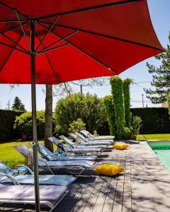 - une rangée de chaises longues et un parasol à côté de la piscine dans l'établissement Le Safari Hotel Restaurant, à Carpentras