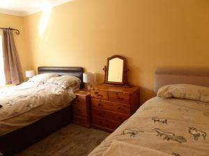 a bedroom with two beds and a dresser and a mirror at Rhydgaled in Llanon