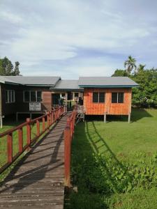 ein Gebäude mit einem Holzsteg neben einem Feld in der Unterkunft AA Homestay in Gunung Mulu Nationalpark