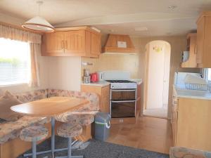 uma pequena cozinha com uma mesa de madeira, uma mesa e cadeiras em 6 Berth with private Garden - 69 Brightholme Holiday Park Brean! em Brean