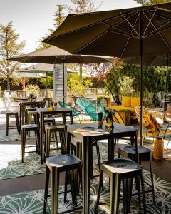 a group of tables and chairs with umbrellas on a patio at Le Safari Hotel Restaurant in Carpentras