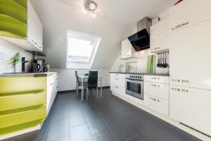 a kitchen with white and green cabinets and a table at Private Apartment in Hannover