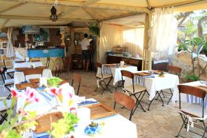 a restaurant with tables and chairs and a man in the kitchen at Hotel Luagos club in Lampedusa