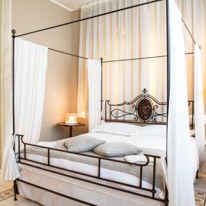 - un lit à baldaquin en fer dans une chambre avec des rideaux blancs dans l'établissement Villa Belverde Boutique Hotel, à Carrara