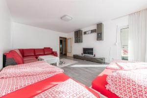 een woonkamer met 2 bedden en een rode bank bij Privatapartment Messe Süd in Hannover