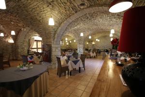 un restaurant avec des tables et des chaises dans un bâtiment en pierre dans l'établissement Logis Hôtel Restaurant Gîte La Bastide du Vébron, à Grospierres
