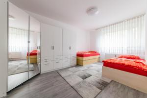 ハノーファーにあるPrivatapartment Messe Südの白いキャビネットと赤いシーツが備わるベッドルームのベッド2台