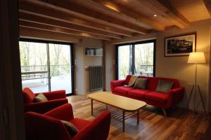 una sala de estar con sofás rojos y una mesa. en Monyoya ,site exceptionnel au coeur des Pyrénées, en Sarrance