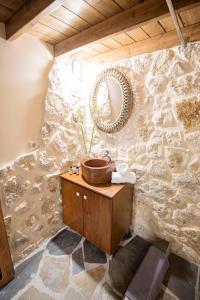 uma casa de banho com paredes de pedra, um lavatório de madeira e um espelho. em Athina house em Rodes