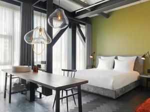 ein Schlafzimmer mit einem Bett und einem Tisch sowie einigen Fenstern in der Unterkunft east Hotel Hamburg in Hamburg