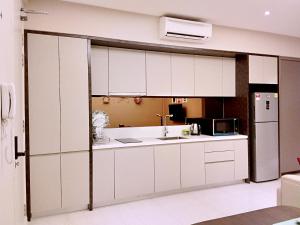 Una cocina con gabinetes blancos y un refrigerador. en SKY POOL Stylish Suite 2-7Pax at KL City, en Kuala Lumpur