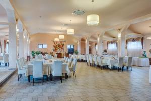 una sala banchetti con tavoli e sedie bianchi di Club Insieme Grand Resort a Potlogi