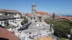una ciudad con una torre del reloj y una calle con coches en La Casona, en Noja