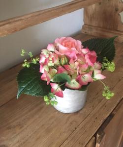 a white vase filled with pink flowers on a table at Ferienwohnung Alte Scheune in Egestorf