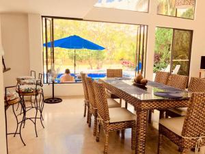 a dining room with a table and chairs and an umbrella at HERMOSA CASAQUINTA FAMILIAR CONDOMINIO CAMPESTRE EL PEÑON Piscina Privada Campo de Golf in Girardot